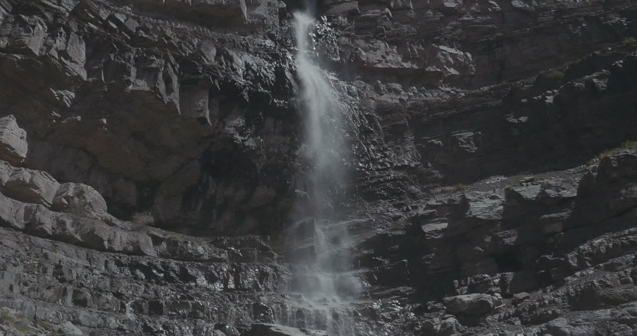 A waterfall running down a layered rock cliff